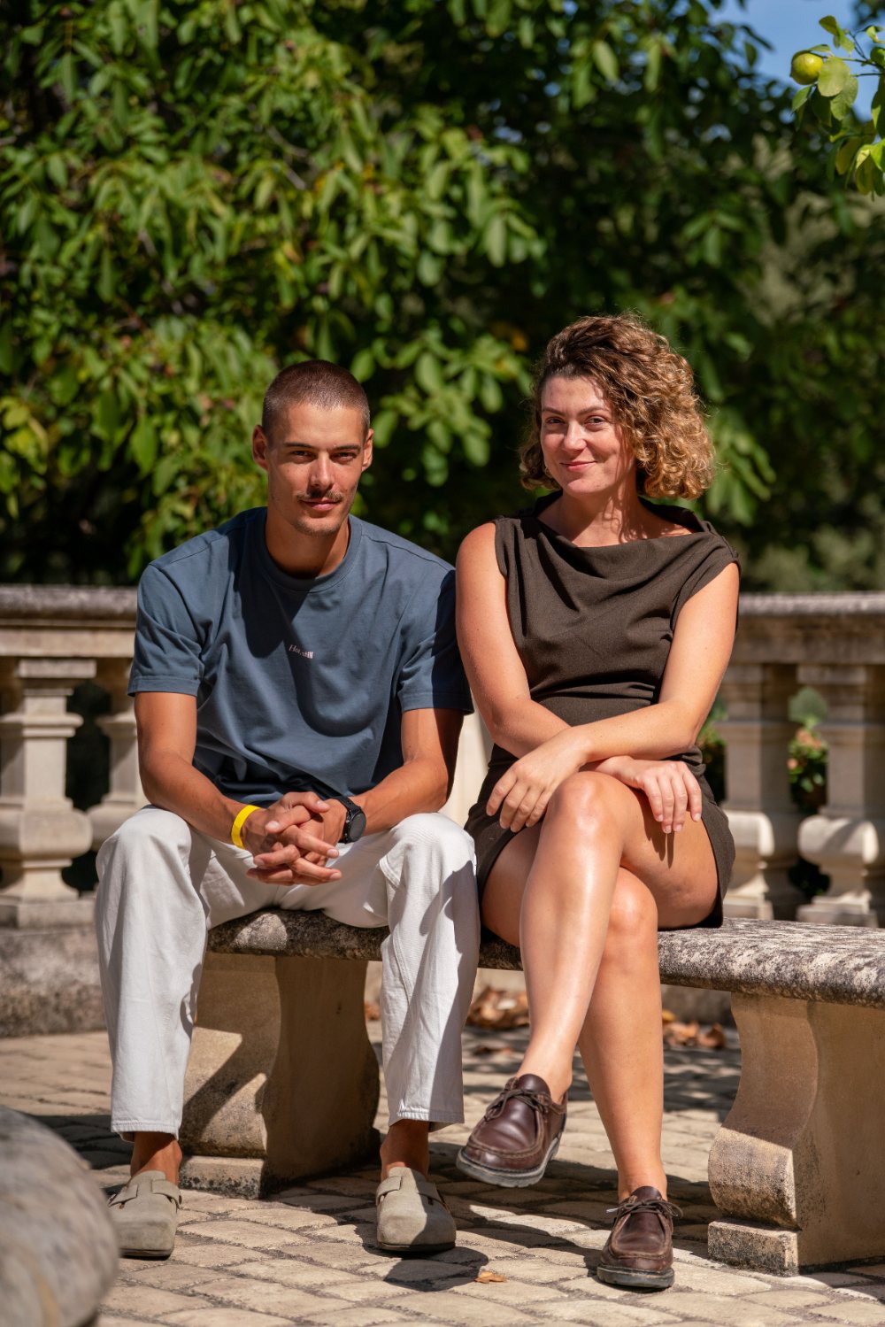 Antoine et Marietta, assis côte à côte sur un banc de pierre, dans un jardin à Marseille